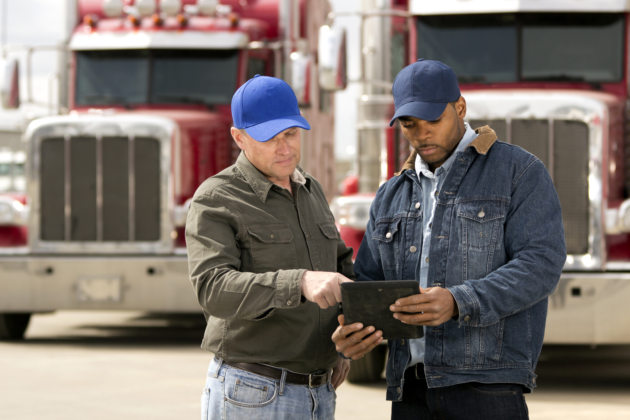 Two truck drivers having a meeting using a tablet computer.